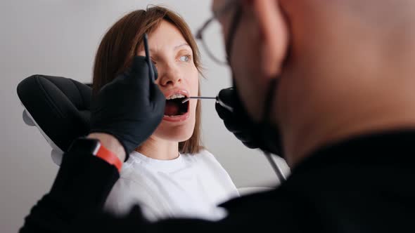 Patient Opening Mouth and Dentist Examining Dentition Work After Surgery