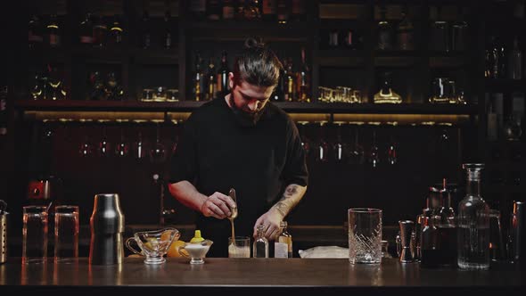 Professional Bartender Stirs Cocktail in Glass with Spatula alt