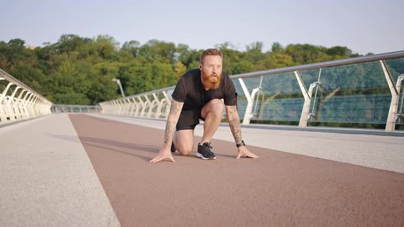 Bearded Athlete Gets Up Starting Low Run on Footbridge alt