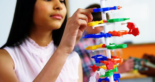 Schoolgirl experimenting molecule model in laboratory at school alt