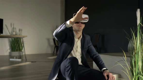 businessman in glasses of virtual reality is sitting on the floor in the office alt