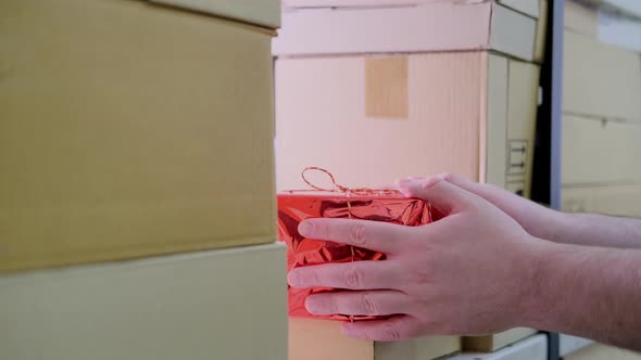 A man hand takes a gift box in the store warehouse for delivery on Christmas Eve on New Year Eve
