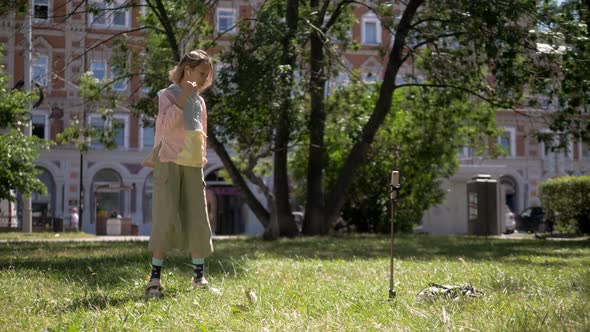 School Girl Take a Selfie on a Phone on a Sunny Day with Tripod Selfie Stick, Kid Dance and Sign in alt