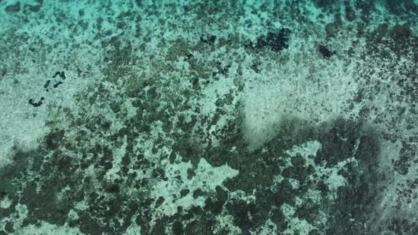 Rising aerial over private yachts parked at luxury island. Top view of seafloor visible from shallow alt