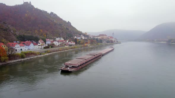 Cargo Pusher Boat on a River Transporting Cargo and Goods Past a Town alt