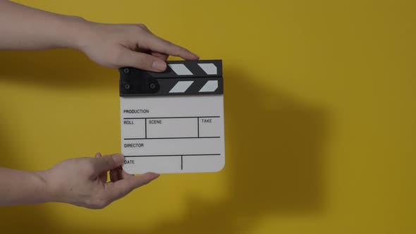 Movie slate or clapperboard hitting. Close up hand holding empty film slate and clapping it. Open alt