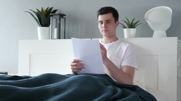 Man Reading Documents in Bed Paperwork alt