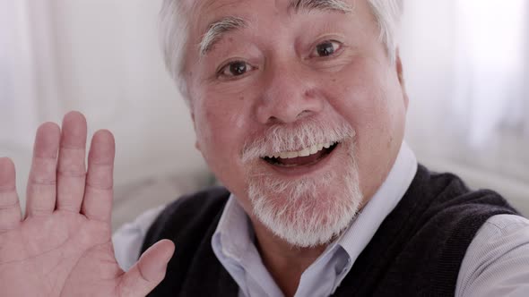 An Asian Elderly video call with smartphone on the sofa on a relaxing day.