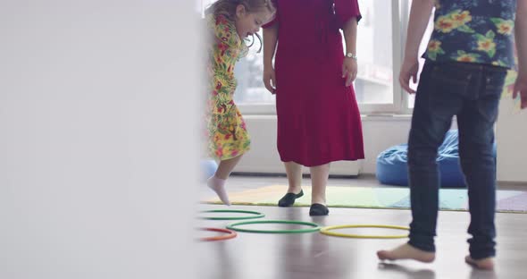 Small Nursery School Children with Female Teacher on Floor Indoors in Classroom Doing Exercise alt