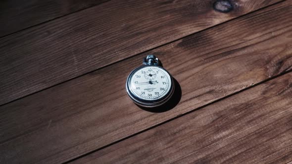 An Antique Stopwatch Lies on Wooden Table and Counts the Seconds Timelapse alt
