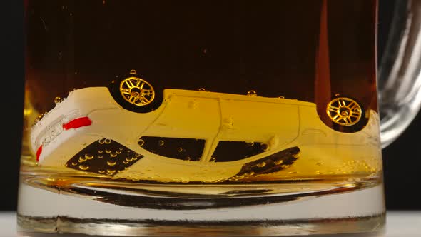 Toy car lies  upside down into a beer mug