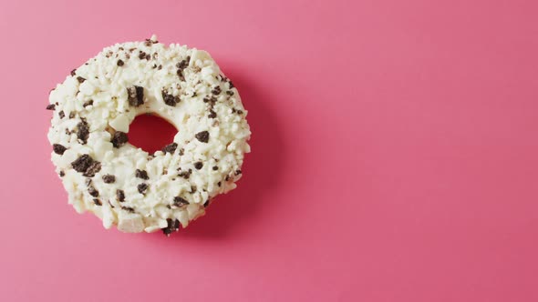 Video of donut with icing on pink background alt
