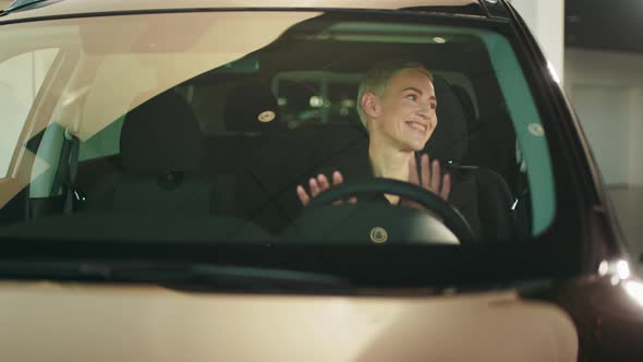 Beautiful Female Customer of Showroom Testing Interior of New Crossover Auto alt