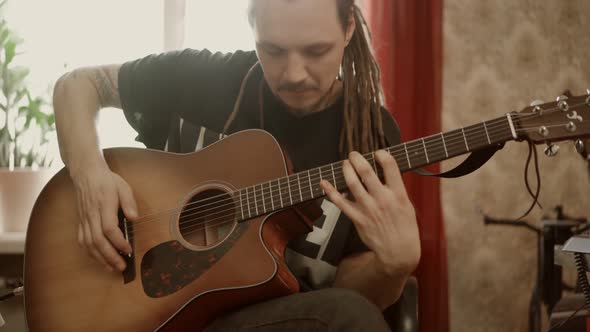 Musician with Dreadlocks Playing Guitar at Home
