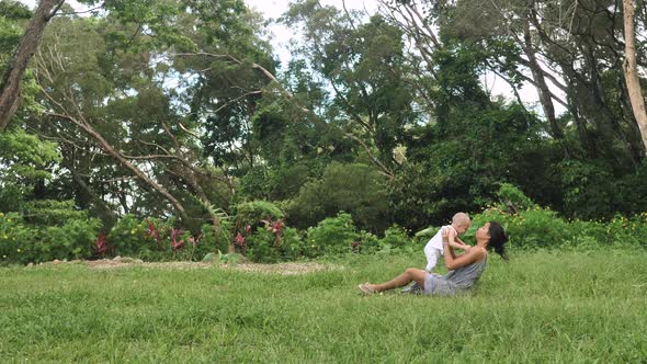 Loving Mother Holding Baby Son in Her Arms Playing with Him Tossing Gently alt