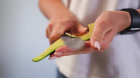 Woman Cuts Out the Middle of an Avocado From Nut with Large Uncomfortable Knife