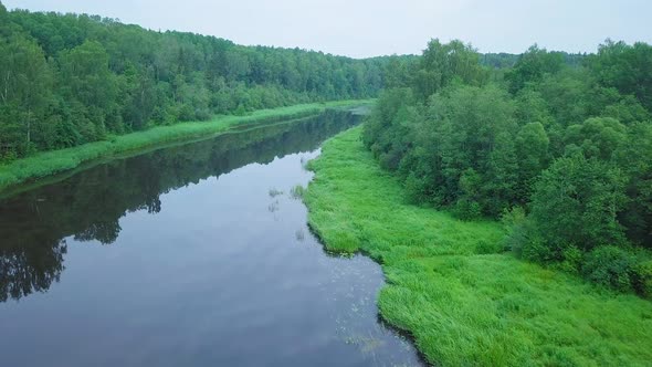 Aerial view of a Venta river (Latvia) on a sunny summer day, lush green trees and meadows, beautiful alt