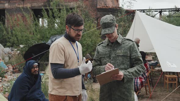 Social Worker Talking to Police Officer at Refugee Camp alt
