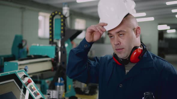 A Male Factory Worker Puts on a Safety Helmet alt