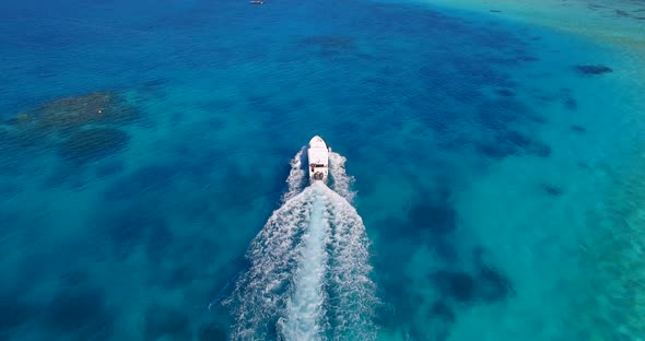 Aerial drone view of a motor boat going to a scenic tropical island in the Maldives. alt