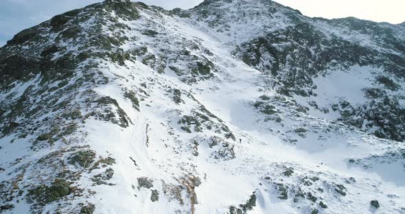 Side Aerial Over Winter Snowy Mountain with Mountaineering Skier People Walking Up Climbing