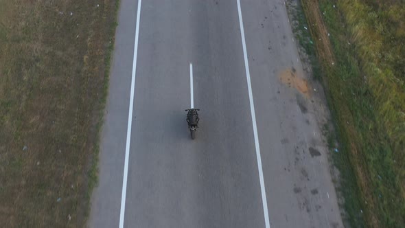 Aerial Shot of Motorcyclist Racing His Motorcycle on Country Road alt