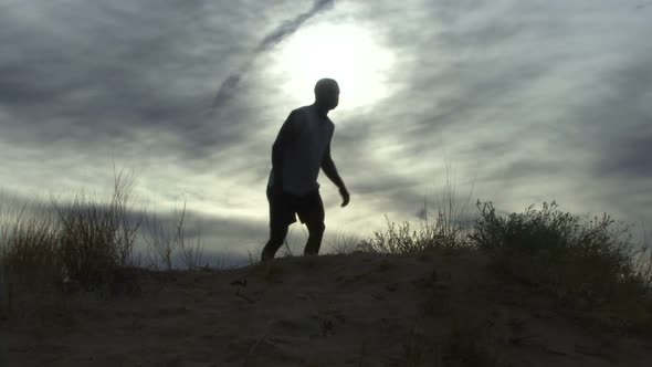Male walking up hill and relaxing alt