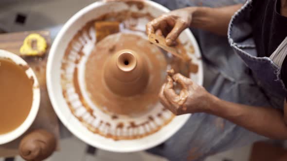 Hands of man at pottery wheel forming clay