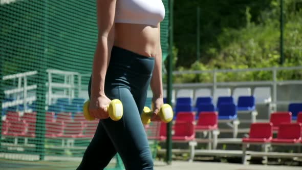 Young Fit Sporty Girl Does Lunge Squat Exercise with Dumbbells at Sports Ground