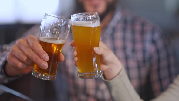 Unrecognizable Man and Woman Clinking Beer Glasses Drinking Pale Lager Indoors alt