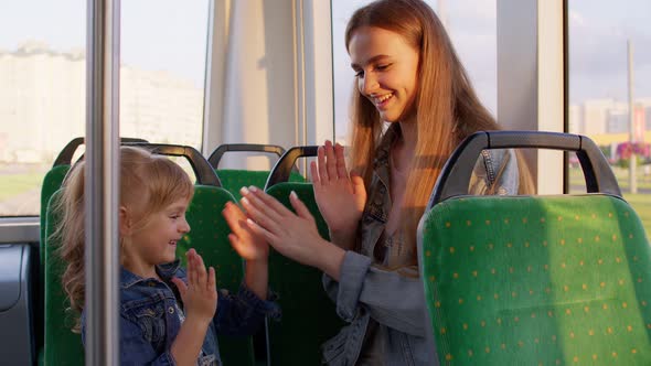 Family Rides in Public Transport Tram Mother with Girl Sit Together and Playing Game Clapping Hands alt