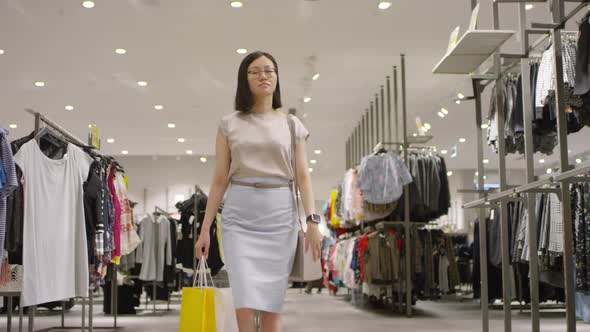 Chinese Female Shopper Walking through Clothing Store alt