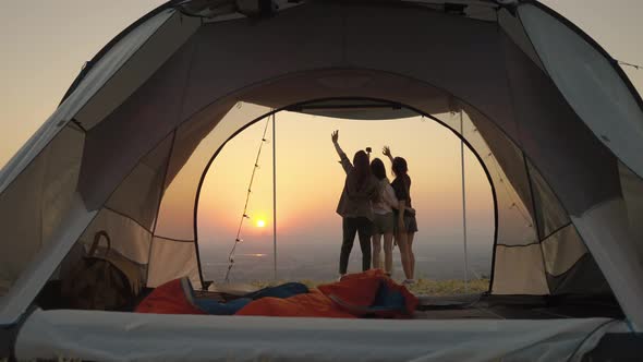 group of young Asian friends standing and taking pictures and relaxing in front of a tent