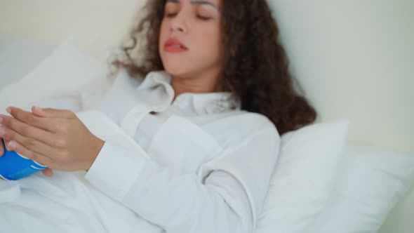 Young Latino sick woman in pajamas take medicine after wake up on bed ...