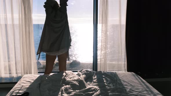Peaceful Happy Young Blonde in Bathrobe Enjoys Beautiful View of Sea Standing Against the Backdrop