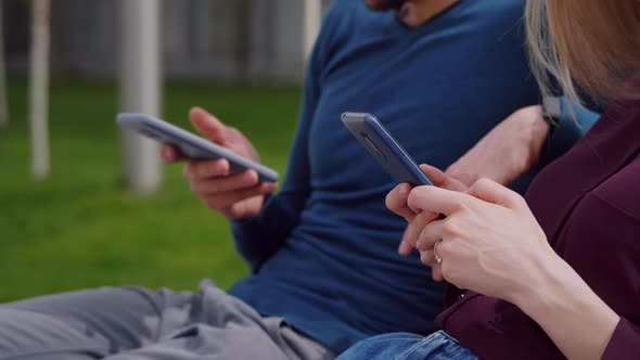 Close up view using smartphones young couple, man and woman holding phones in hands alt