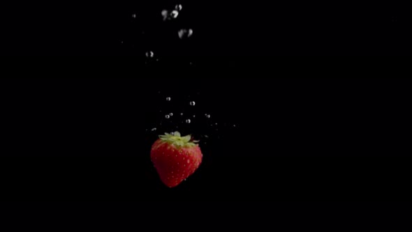 Strawberry Falling into Water Super Slowmotion, Black Background, lots of Air Bubbles, 4k240fps alt