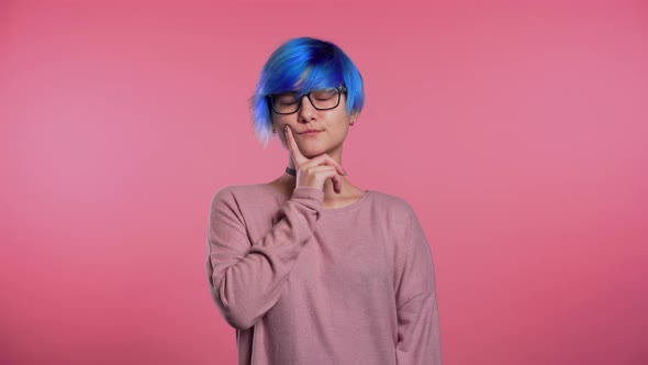 Thinking Woman with Blue Hair Looking Up and Around on Pink Background. Worried alt
