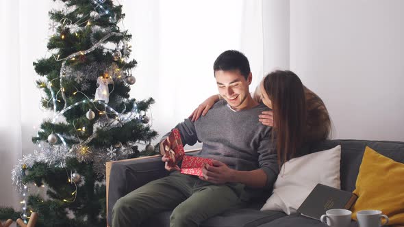 Woman Giving Surprise Christmas Gift for Man.