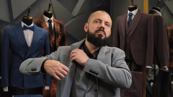 Successful Businessman with a Beard Puts on a Jacket in a Tailor Shop. Satisfied Customer on the alt