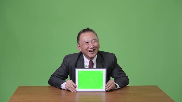 Mature Japanese Businessman Showing Digital Tablet alt