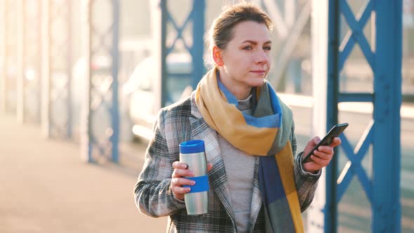 Portrait of a Young Caucasian Businesswoman in a Coat Walking Across the Bridge on a Frosty Morning alt