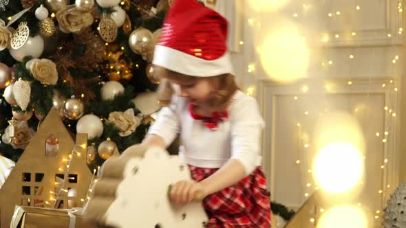 Little Happy Child Girl Rocks Wooden Rockinghorse on Background of Christmas Tree