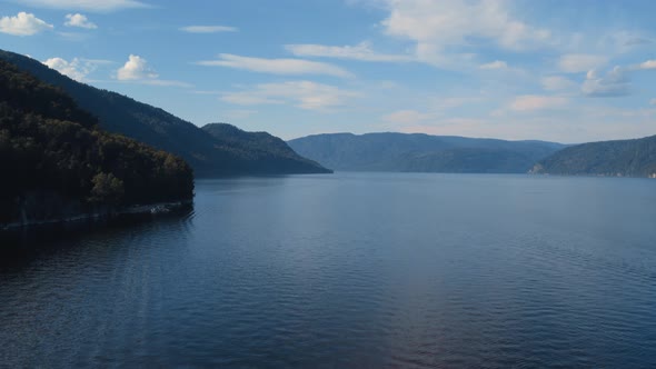 Coastline of lake Teletskoye with forest and blue clear sky in Altai alt
