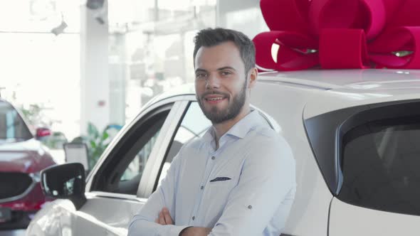 Attractive Young Man Holding Car Keys To His New Automobile at Dealership alt