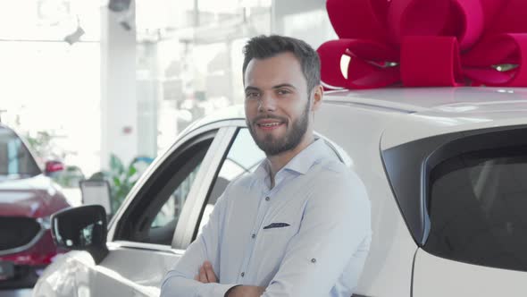 Attractive Young Man Holding Car Keys To His New Automobile at Dealership