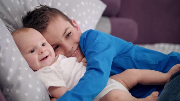 Portrait of Boy Embracing Infant. Happy Siblings with Baby. Happy Brothers alt