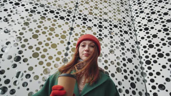 Portrait of Woman with Coffee Cup in front of Urban Building alt