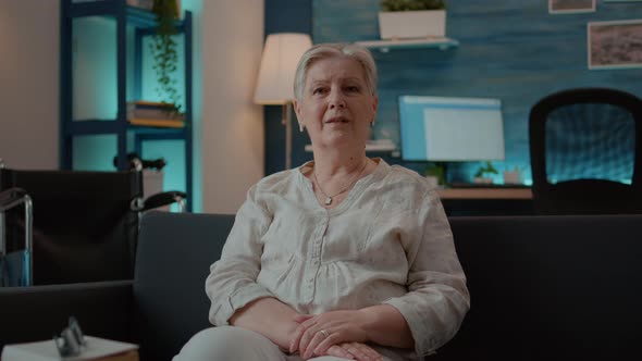 Portrait of Senior Woman with Physical Injury Sitting on Couch alt