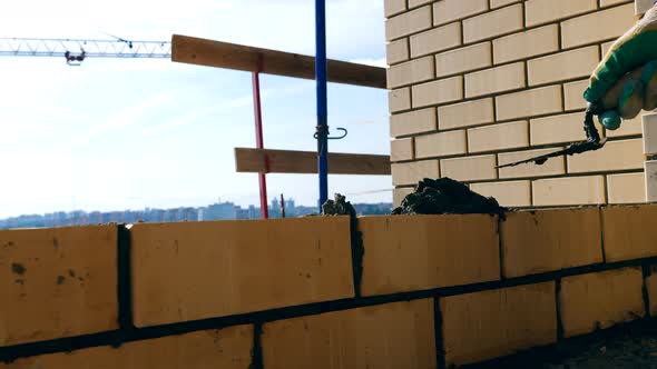 One Person Lays Bricks While Building a House. Bricklayer Doing Brickwork at a Construction Site. alt